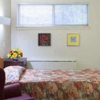 A cozy bedroom with a single bed, floral bedspread, and decorative wall art.