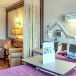 A well-furnished hospital room with medical equipment and seating area.