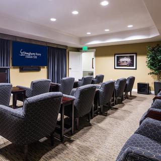 A small conference room with rows of upholstered chairs facing a projector screen.