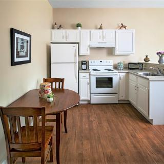 A cozy kitchen with white cabinets, appliances, and a small dining table.