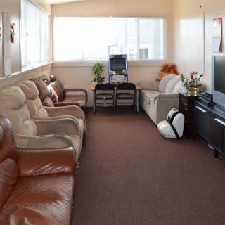 A cozy living room with couches, armchairs, a television, and large windows.
