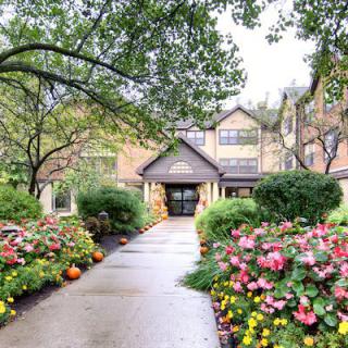 A picturesque garden pathway lined with colorful flowers leads to a charming building.