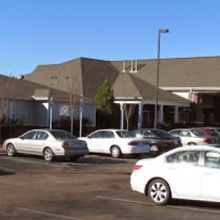 A view of a commercial building with a parking lot filled with cars on a clear day.