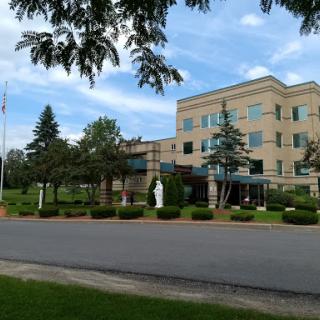A view of a healthcare facility surrounded by greenery and under a blue sky.