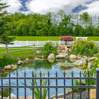 A serene pond surrounded by lush greenery and rocky formations, inviting a peaceful escape into nature.