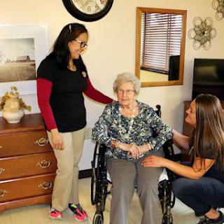A warm moment shared between caregivers and an elderly woman in a comfortable indoor setting.
