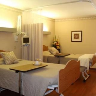 A well-lit hospital room featuring two patient beds with privacy curtains and medical equipment.