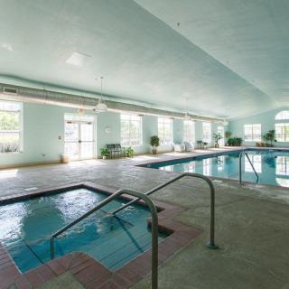 An indoor facility featuring a swimming pool and jacuzzi surrounded by large windows.
