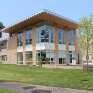 A modern architectural building with expansive glass windows surrounded by lush green grass.