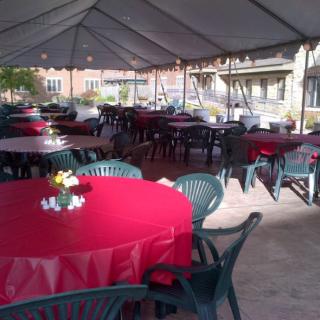 Outdoor event setup with tables covered in red tablecloths under a tent.