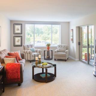 A cozy living room with comfortable seating, large windows letting in natural light, and tasteful decor.