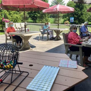 A group of people enjoying an outdoor bingo game under umbrellas.
