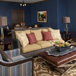 A cozy living room with a beige sofa, colorful cushions, blue walls, and elegant decor.