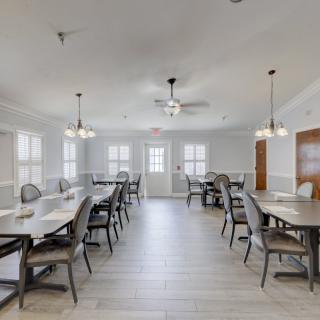 A modern dining area with multiple tables and chairs, well-lit by ceiling lights.