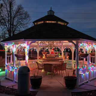 A beautifully decorated gazebo with colorful Christmas lights shining brightly in the evening.