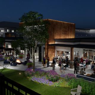 An inviting outdoor dining area at night, featuring modern architecture and vibrant landscaping.