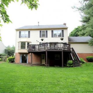 A two-story house with a spacious deck overlooking a green backyard.