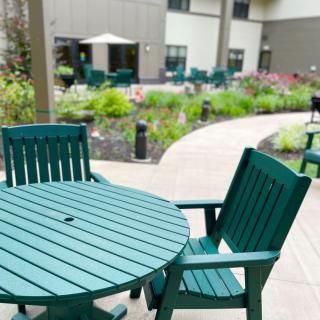 An outdoor patio area featuring green tables and chairs with a garden pathway.