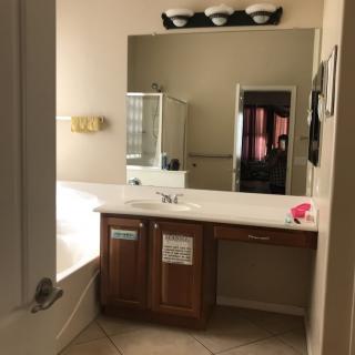 A modern bathroom with a large mirror, single sink vanity, and bathtub.