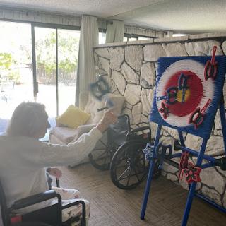 An elderly person engaged in a target game activity indoors, promoting rehabilitation and exercise.