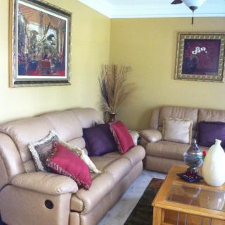 A cozy living room featuring leather sofas, colorful cushions, and framed artwork on the walls.