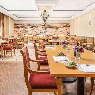 A well-decorated dining area with neatly arranged tables and chairs, featuring elegant lighting and wall art.