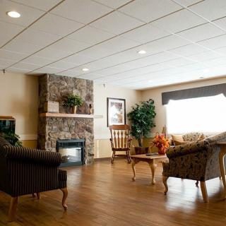 A cozy living room with sofas, a stone fireplace, and wooden flooring.
