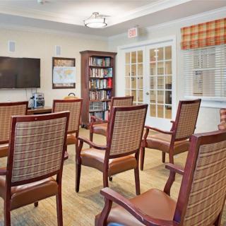 A cozy meeting room with arranged chairs, a bookshelf, and a television.