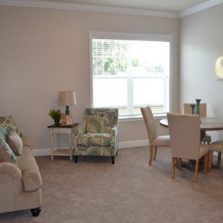 A cozy living room with a dining area, featuring comfortable seating and a large window.