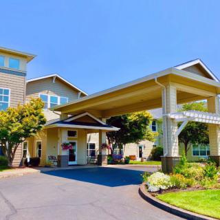 A modern building entrance with a covered driveway and landscaped surroundings.