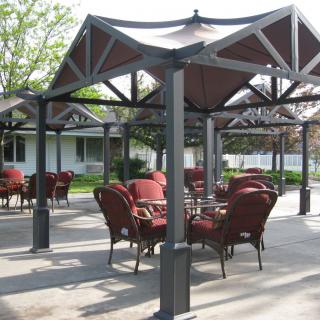 An outdoor patio area with tables and chairs under a gazebo.