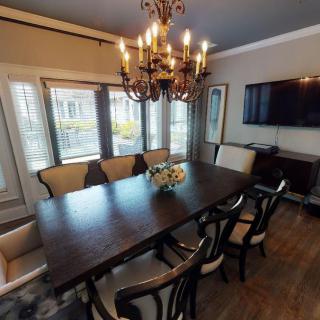 A well-appointed dining room featuring a large wooden table, elegant chandelier, and wall-mounted TV.
