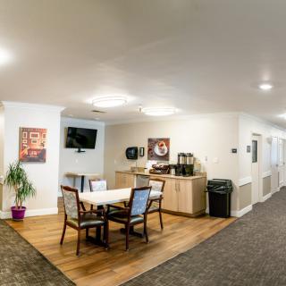 A cozy seating area in a hallway with a table, chairs, and a coffee station.