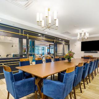A stylish and modern dining room featuring a long wooden table surrounded by blue chairs, perfect for meetings or gatherings.
