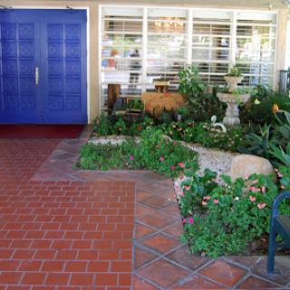 A welcoming garden entrance featuring vibrant blue doors and a beautifully landscaped path.