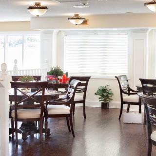 A well-lit dining area featuring stylish dark wood tables and chairs, with decorative plants adding a touch of greenery.