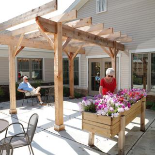 A pergola-covered patio with seating and a flower planter.