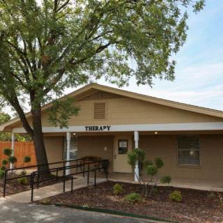 A small library building with a ramp and tree in front.