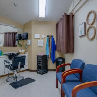 Interior view of a hair salon with styling chair, mirrors, and waiting area.