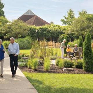 A couple enjoys a stroll through a beautifully landscaped garden, surrounded by greenery and fellow visitors.