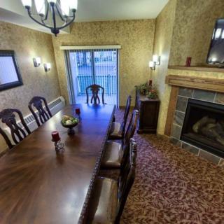 A cozy dining room featuring a long wooden table, elegant chairs, and a warm fireplace.