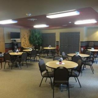 A spacious dining area featuring round tables and chairs, suitable for meetings or gatherings.