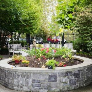 A peaceful garden with colorful flowers surrounded by a stone wall and benches.