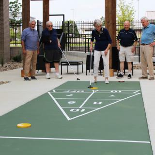 A group of seniors playing shuffleboard outdoors.