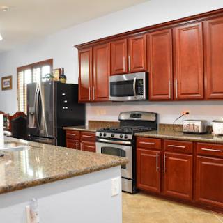 A modern kitchen featuring rich wooden cabinets, stainless steel appliances, and a spacious granite countertop.