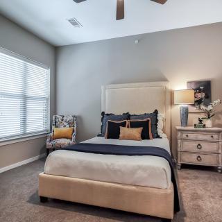 A modern and cozy bedroom with a neatly made bed, stylish armchair, and soft lighting.