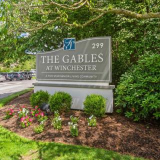 Sign for The Gables at Winchester surrounded by lush garden.