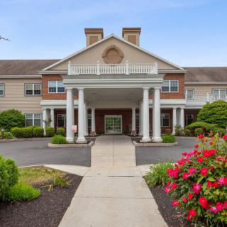 A welcoming entrance to a building with columns and landscaped gardens.