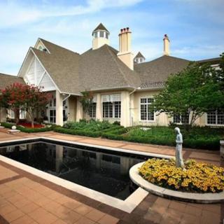 A beautiful house with a manicured garden and fountain in the foreground.