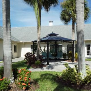 A serene outdoor space featuring a gazebo surrounded by lush greenery and palm trees.